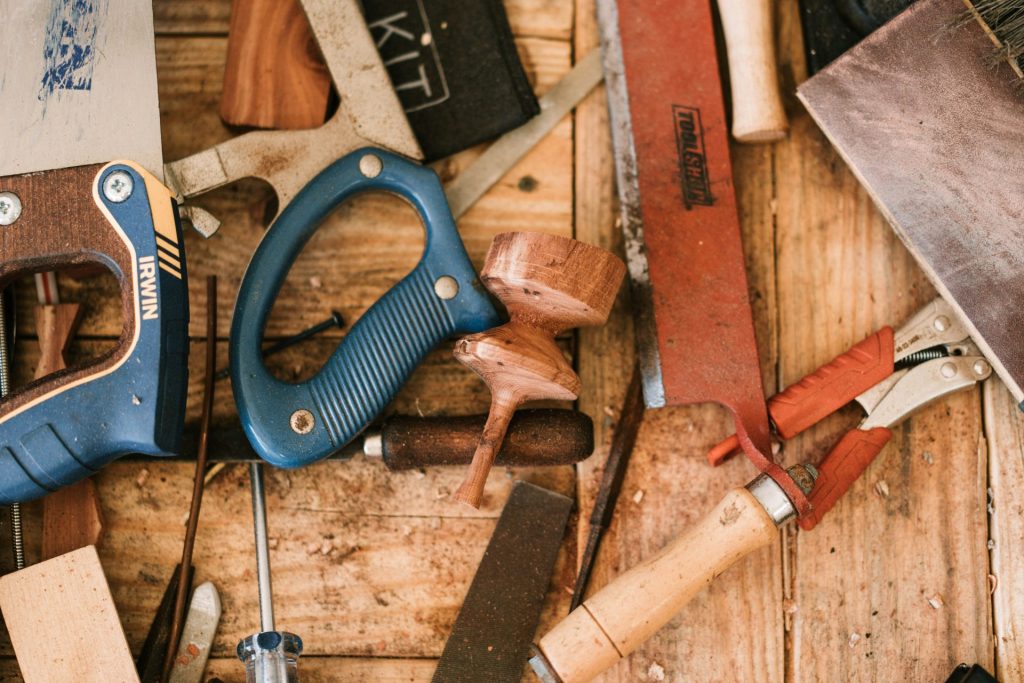 Zange mit blau-schwarzem Griff neben braunem Holzgriff